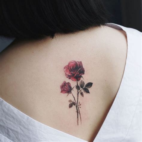 A Woman S Upper Back Tattoo With Three Roses On Her Left Shoulder And Lower Back