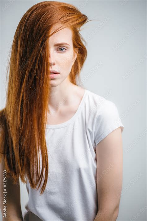 Portrait Of Young Pretty Redhead Girl With Freckles Looking At Camera