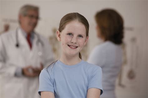 girl in doctor s office while with mother and doctor talk in background free photo download