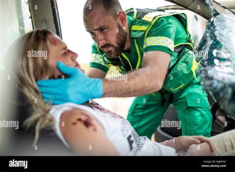 Police Officer With Paramedics Rescuing Car Accident Victim Stock Image