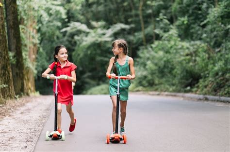 Free Photo Two Female Friends Riding Push Scooters On Street