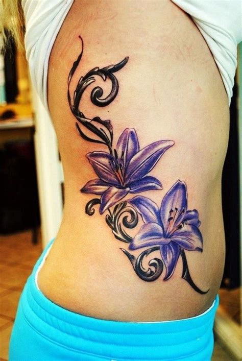 A Womans Lower Back Tattoo With Purple Flowers And Swirls On The Side