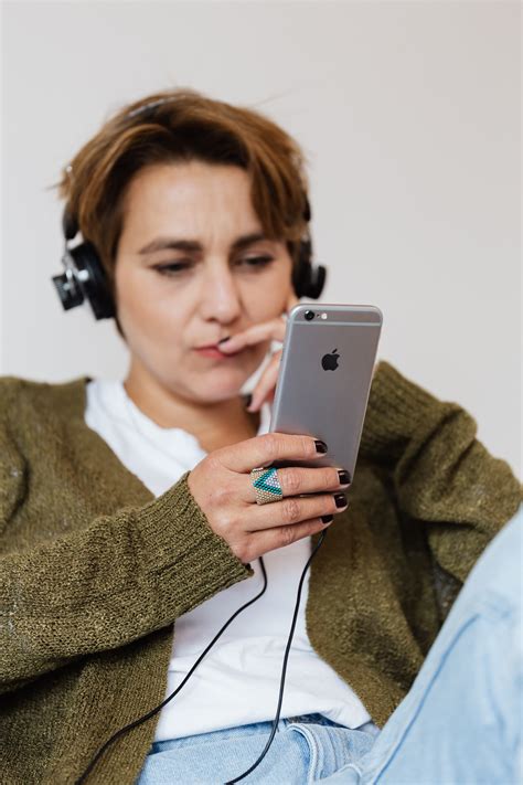 Contemplative Woman Listening To Songs In Headphones Connected To