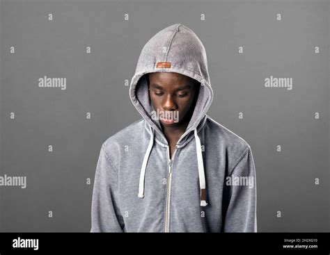 Young Black Man Wearing A Grey Hoodie Looking Down With A Serious
