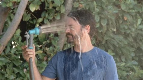 Slow Motion Of Model Released Man Spraying Himself In The Face With A Hose Outside On A Hot