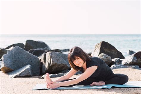 Content Woman Practicing Yoga In Janu Sirsasana On Beach Stock Photo
