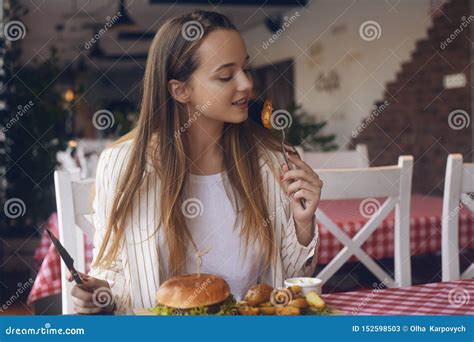 Brunette Girl With Long Hair In A Restaurant Appetizing Eating Potatoes
