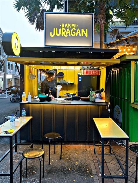 An Outdoor Food Stand With Tables And Stools On The Side Of The Street