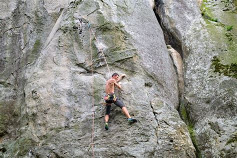 Young Man Climbing Steep Wall Of Rocky Mountain Male Climber Overcomes