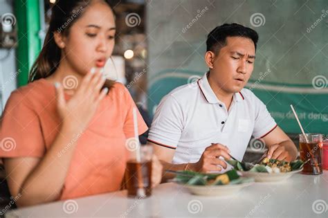 Man With Spicy Expression Eating Pecel With Asian Woman Stock Image