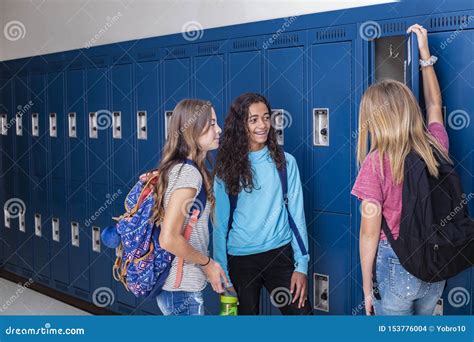 Junior High School Students Talking And Standing By Their Locker In A