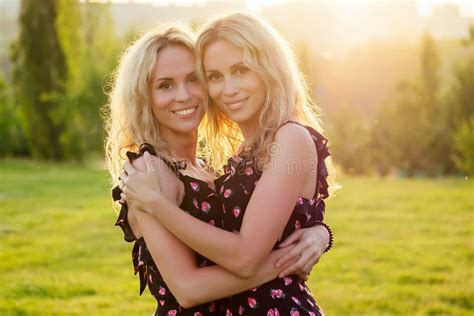 Two Sisters Twins Beautiful Curly Blonde Happy Young Toothy Smile Women In Stylish Dress Hugging