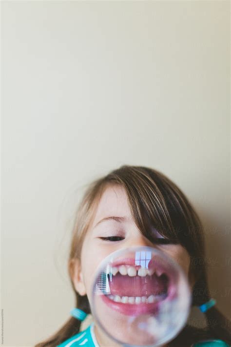Girl Smiles Wide Through Magnifying Glass By Stocksy Contributor Amanda Worrall Stocksy
