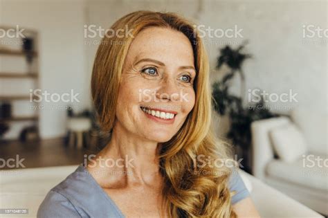 Horizontal Portrait Of Attractive Mature Woman Relaxing On Couch In Elegant Modern Living Room