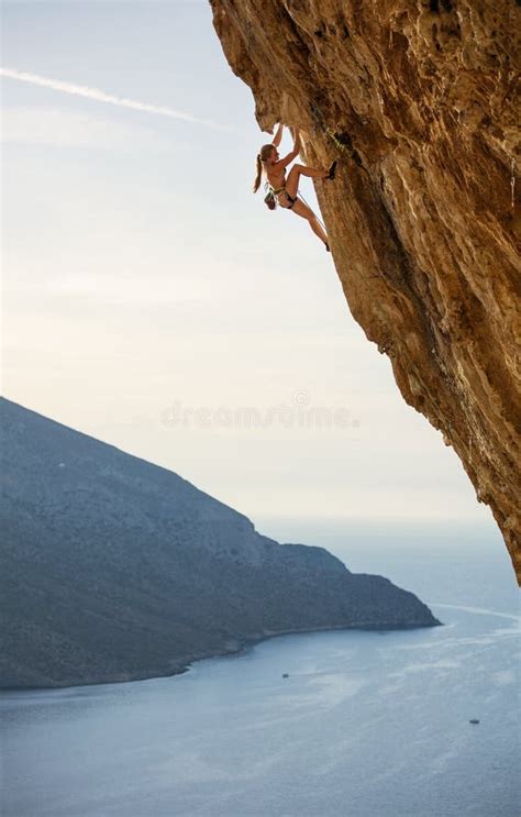 Young Female Rock Climber On Challenging Route On Overhanging Cliff