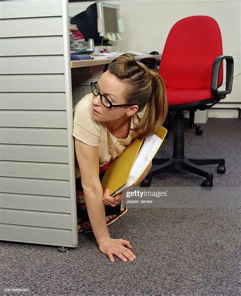 Businesswoman Under Desk In Office Holding Yellow Folder Foto Stock