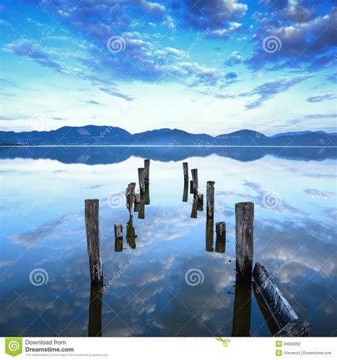 Wooden Pier Or Jetty Remains On A Blue Lake Sunset And Sky