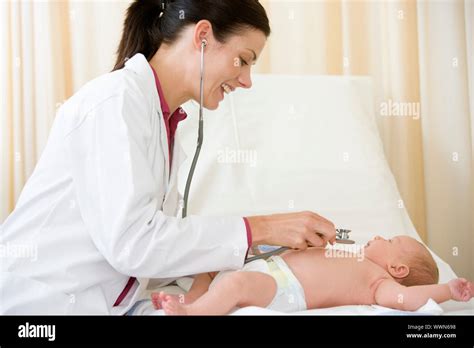 Doctor Giving Checkup With Stethoscope To Baby In Exam Room Smil Stock