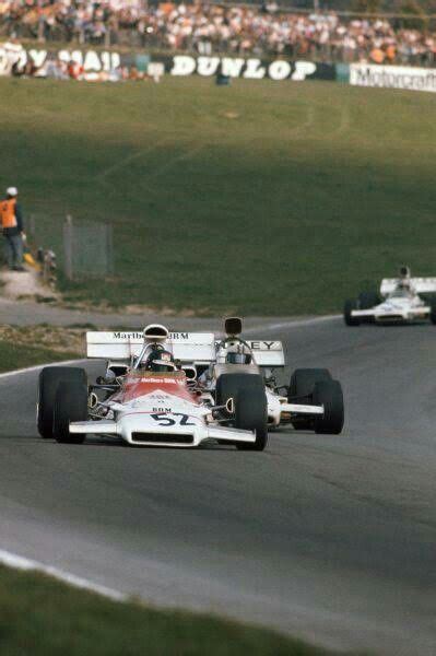 Two Racing Cars On A Race Track With People Watching From The Sidelines