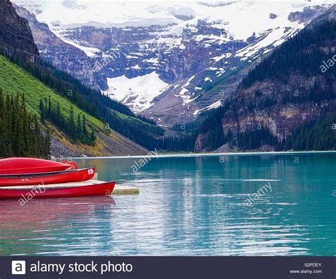 Snow Capped Mountains And Red Canoes And Dock In Lake Louise At Banff
