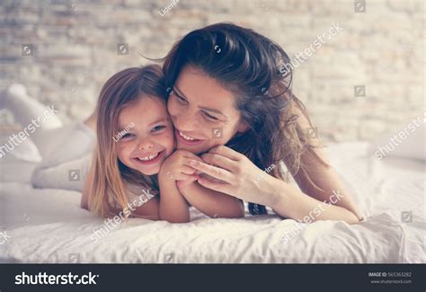 Стоковая фотография 565363282 Мать и дочь наслаждаются в постели shutterstock