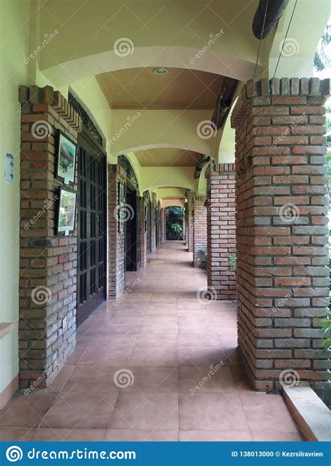 Hallway With Red Brick Columns And Brown Tiled Floors And Cream Ceiling