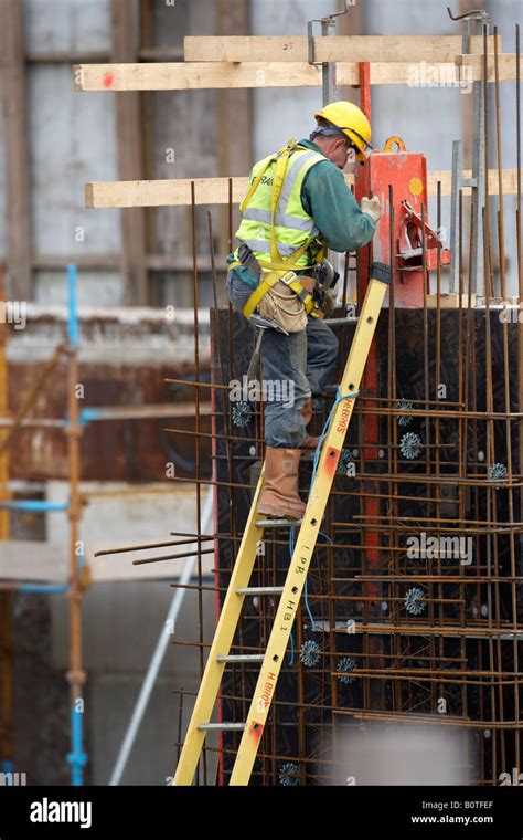 Worker Wearing Full Safety Gear And Harness Climbing Ladder On A