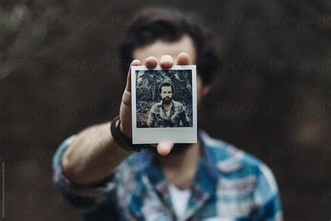 Man Holding Polaroid Portrait Of Self In Forest By Stocksy