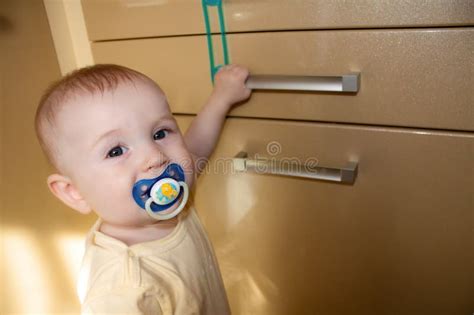 Baby 8 9 Months Tries To Open The Door Cupboard Stock Photo Image Of