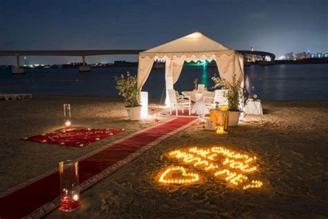 A Wedding Setup On The Beach At Night With Candles Lit Up In The Shape