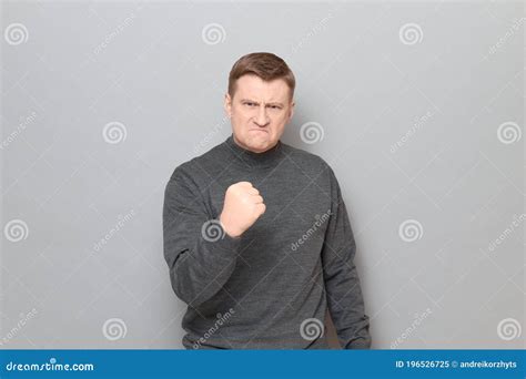 Portrait Of Furious Mature Man Shaking Fist In Threatening Gesture