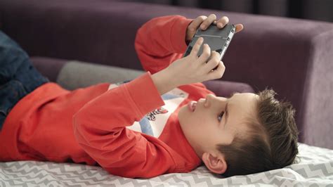 Boy Playing Mobile Game On Smartphone On Sofa Preschooler Playing