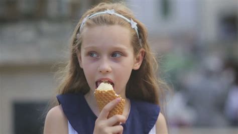 little blonde girl eats licks an ice cream cone on a park bench portrait stock footage video