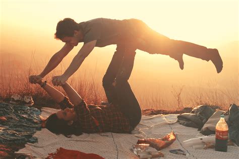 Free Photo Woman Lying On Blanket Under Man On Her Legs Holding Hands During Golden Hour