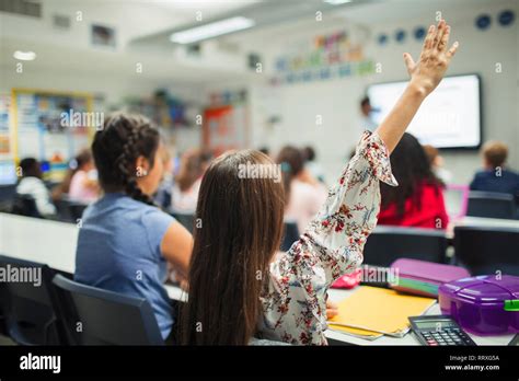 Junior High School Girl Student With Hand Raised In Classroom Stock