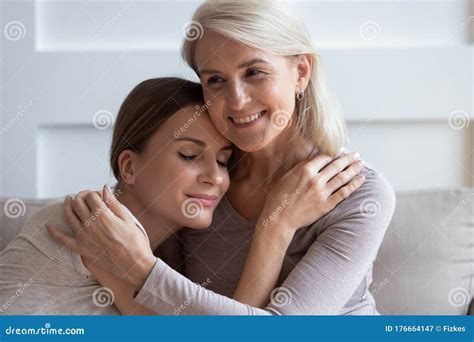 Smiling Older Mother Hugging Calm Adult Daughter Enjoying Tender