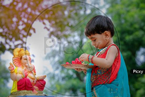 Image Of Indian Girl Child Offering Prayer To Hindu Elephant Headed God