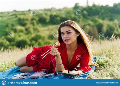 Attractive Girl With 3 Sushi Sets Lays On The Blue Cover On Green Hills