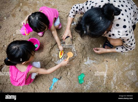 Asian Chinese Mum And Daughter Playing Sand Together At Seaside Stock