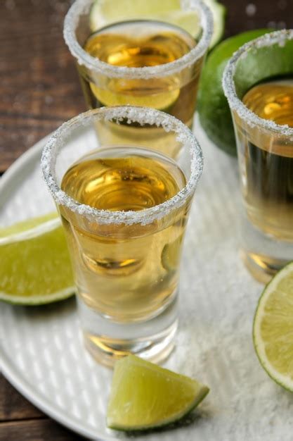 Premium Photo Gold Tequila In A Glass With Salt And Lime On A Brown Wooden Table Alcoholic