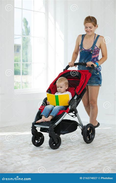 Caucasian Young Woman Pushing Stroller With Toddler Boy Indoors Stock