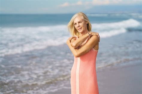 Older Woman Enjoying Her Free Time Looking At The Sea From The Shore Of
