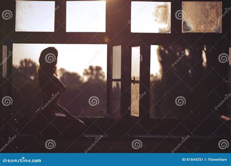 Beautiful Naked Female Sitting On A Window At Sunset Stock Image