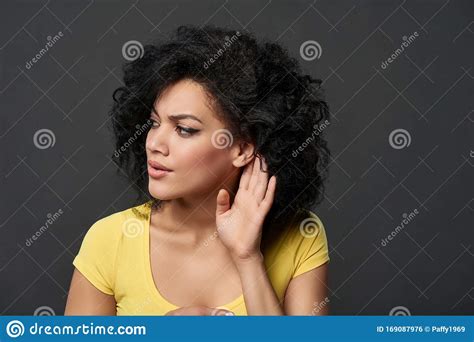 Serious Woman Listening Gossip With Palm Shielding Ear Stock Photo