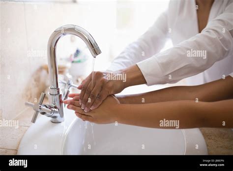 Mid Section Of Grandmother And Granddaughter Washing Hands At Bathroom