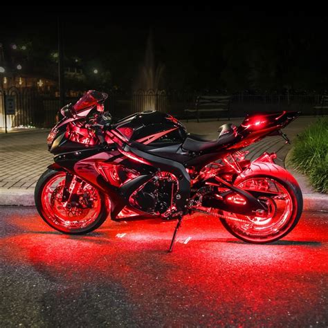 A Red Motorcycle Parked On The Side Of A Road Next To A Street Light At