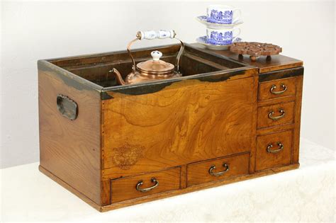 An Old Wooden Box With Two Tea Kettles On Top And Cookies In The Bottom