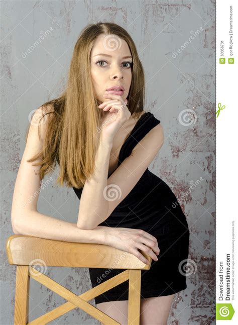 Slim Beautiful Red Haired Girl In A Black Mini Dress With A Chair Stock