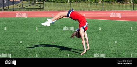 A Hifh School Cheerleader Is Upside Down As She Practices Her Running