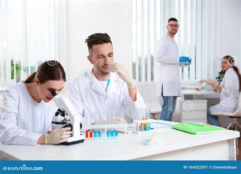 Scientist With Microscope And Colleagues In Laboratory Stock Image
